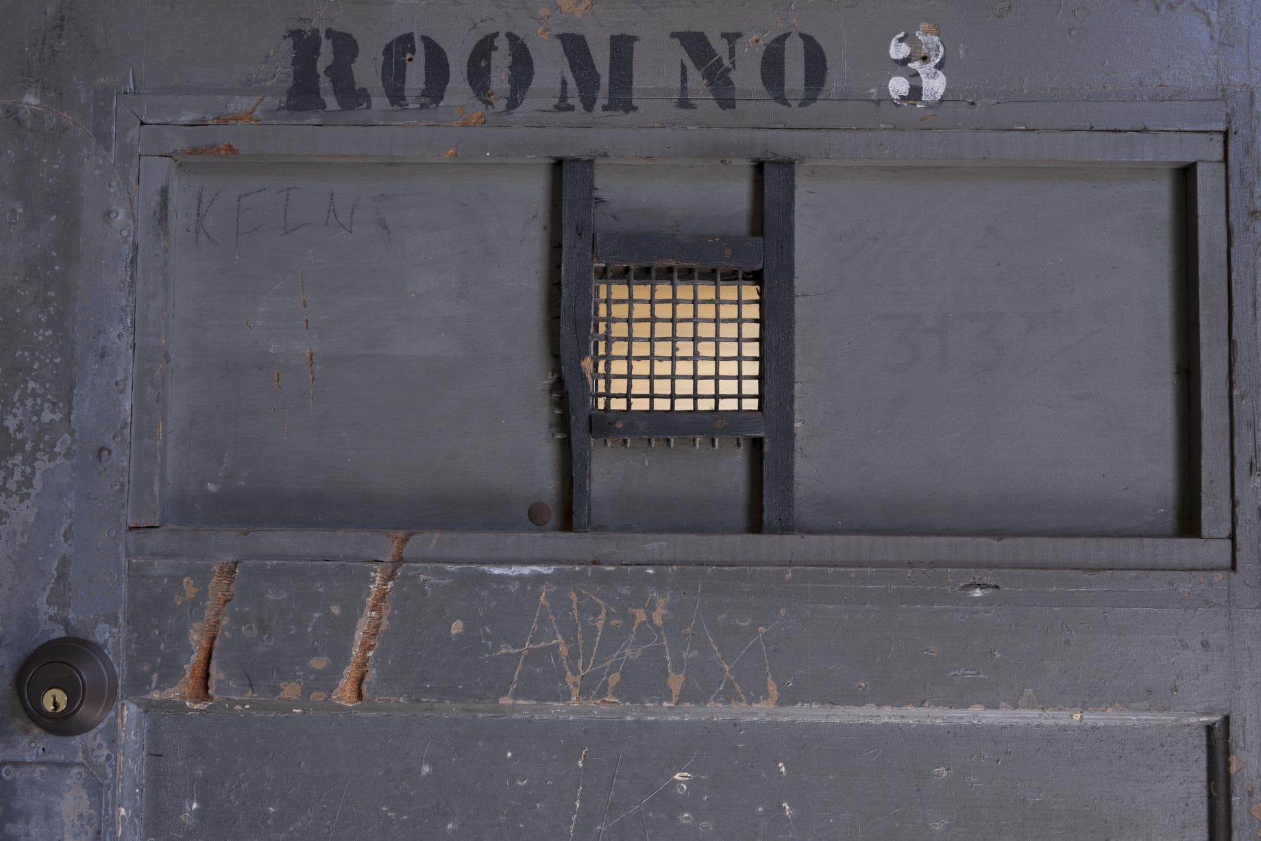 A barracks door stencilled Room No. 3, still scratched and written on.
