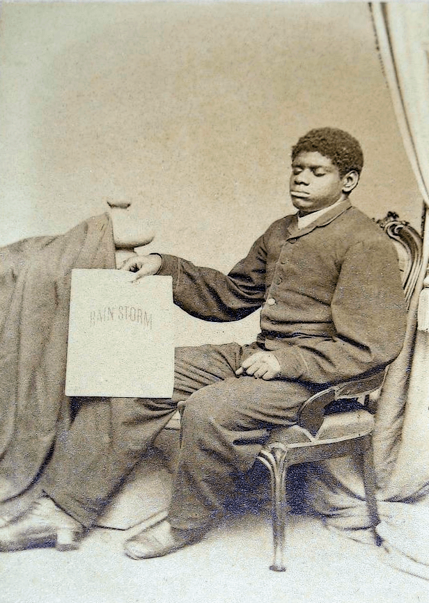 Wiggins holding a copy of his first composition, The Rain Storm, photographed about 1861.