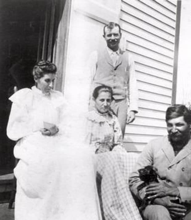 With relatives on the steps. The record does not say which figure is which.