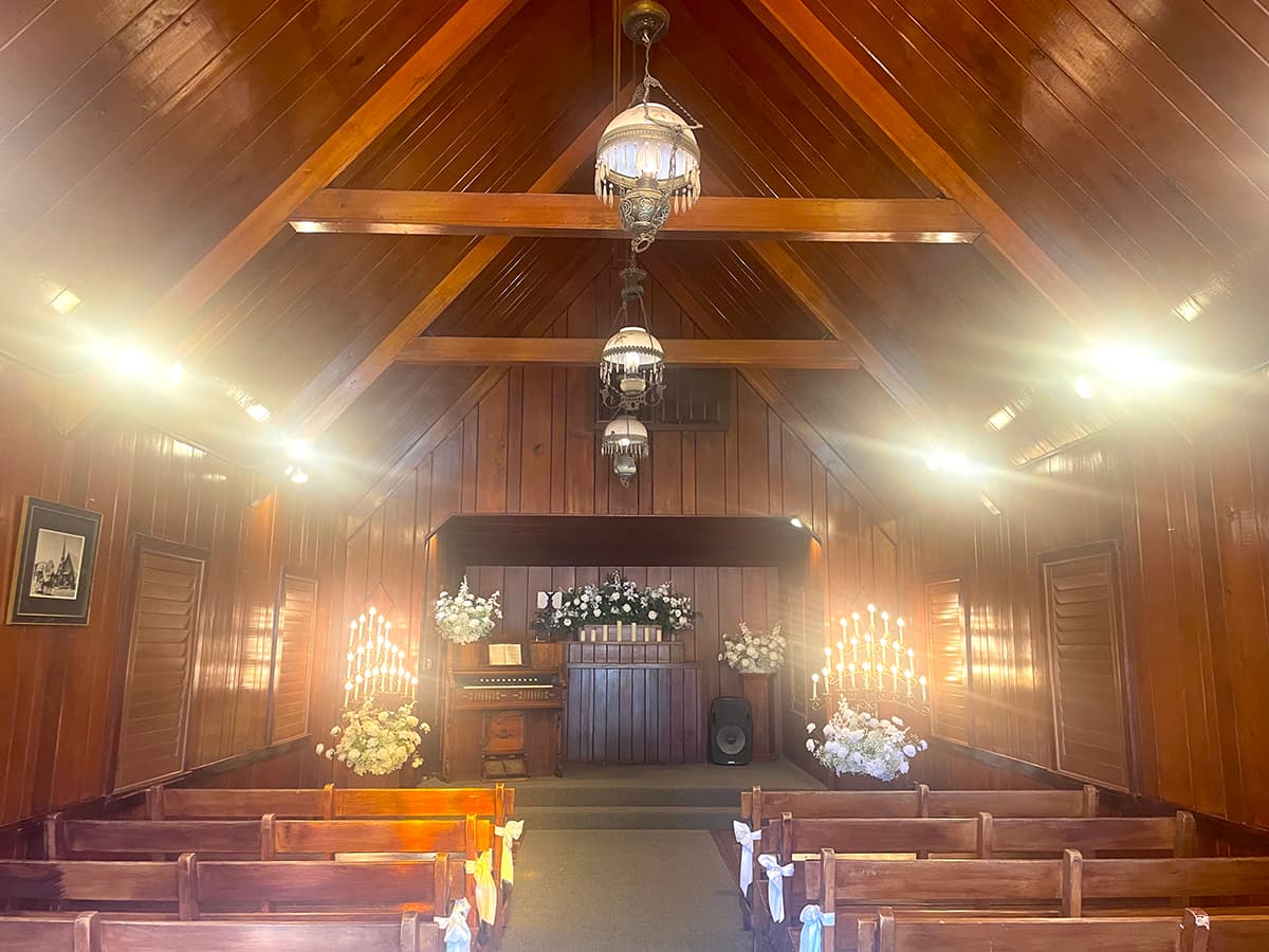 Inside: pine beams, wooden pews, and flowers at the altar.