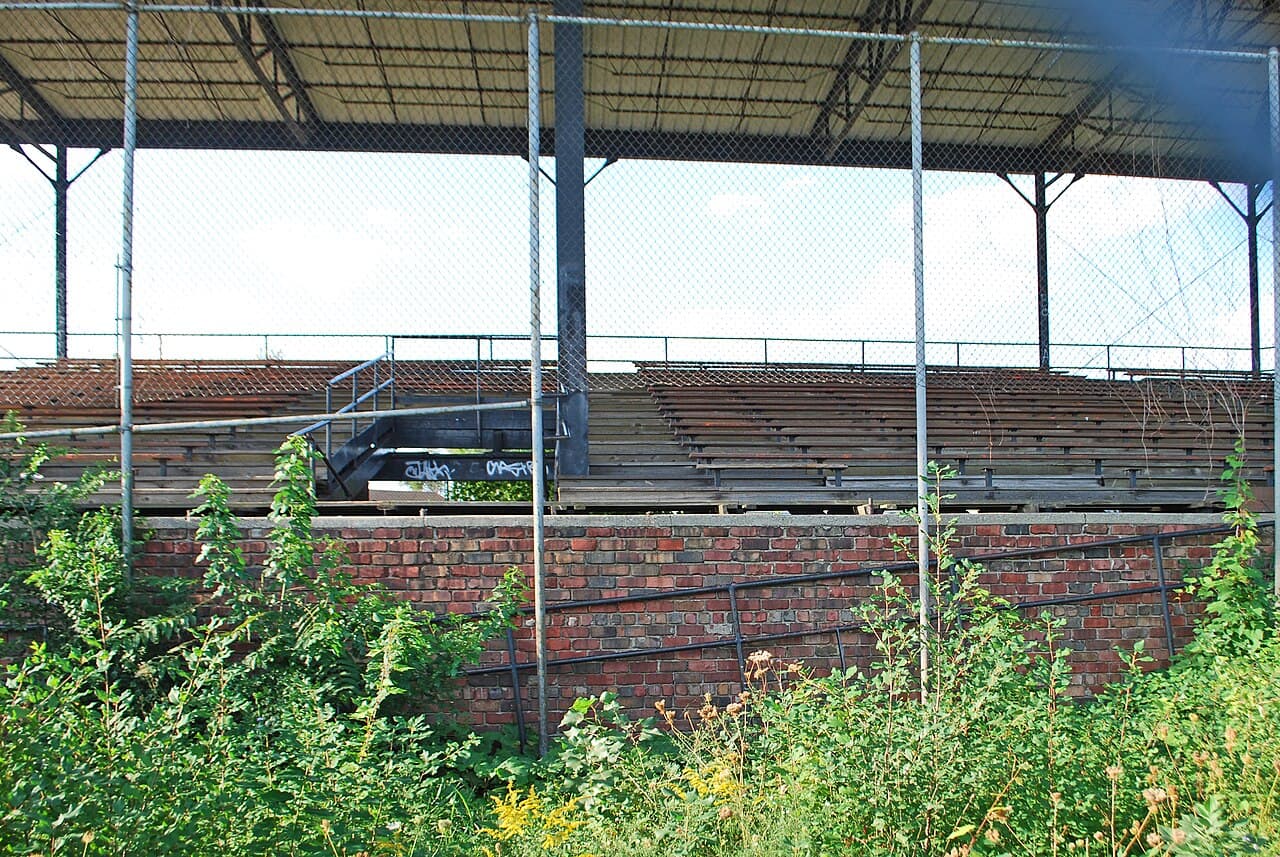The bleachers under the grandstand roof, weeds coming up through the concrete.